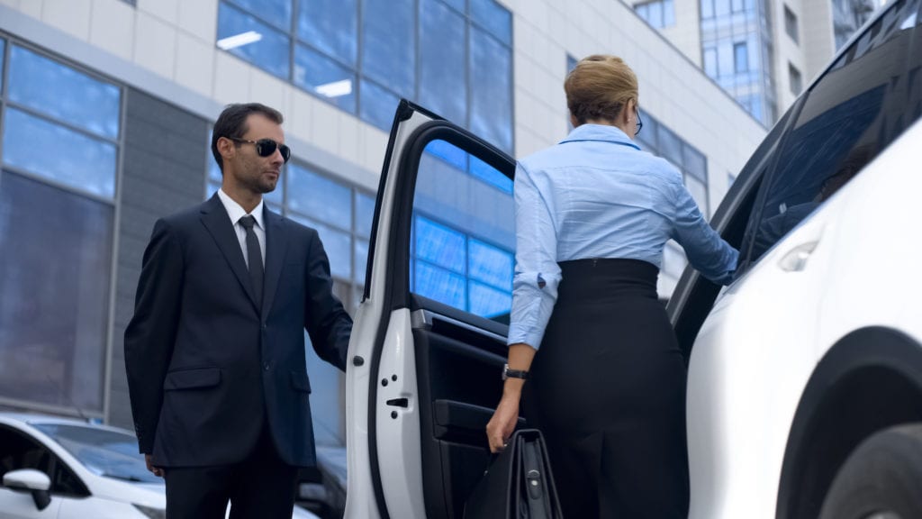 Body guard holding car door for client