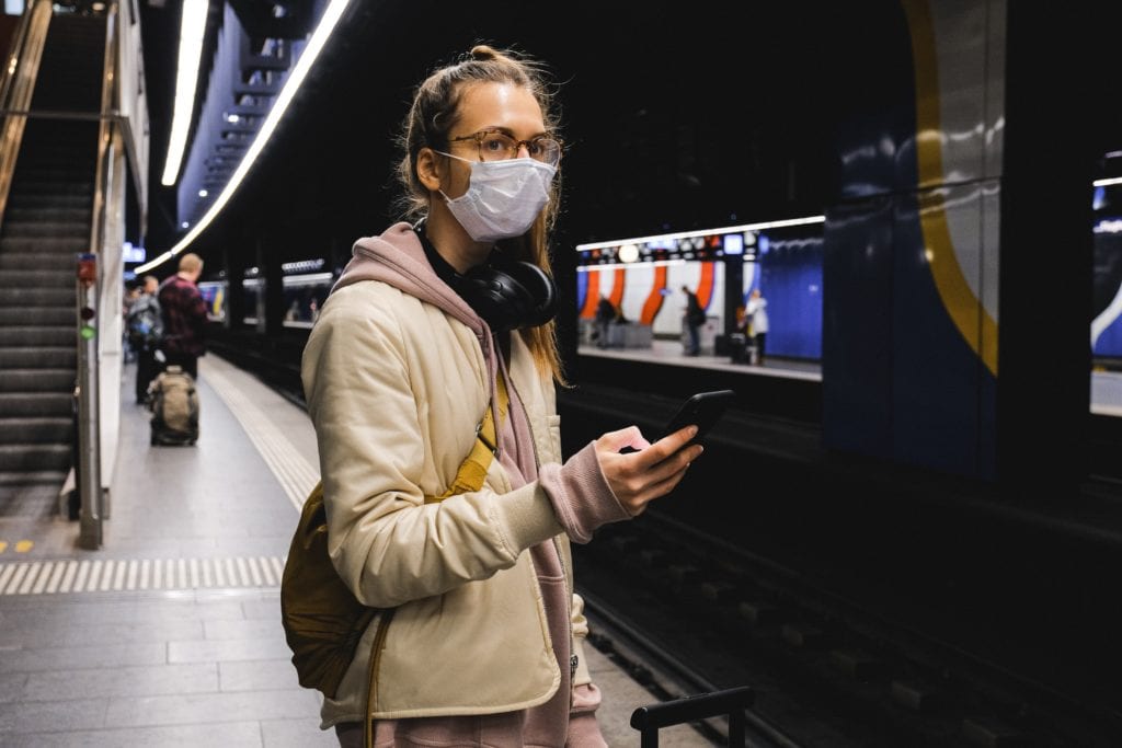 Girl  in mask waiting for a train